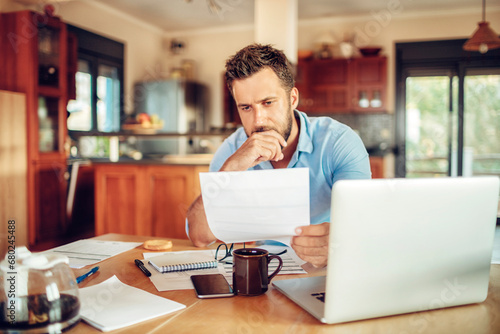 Foto Young man looking at paper document with concern at home