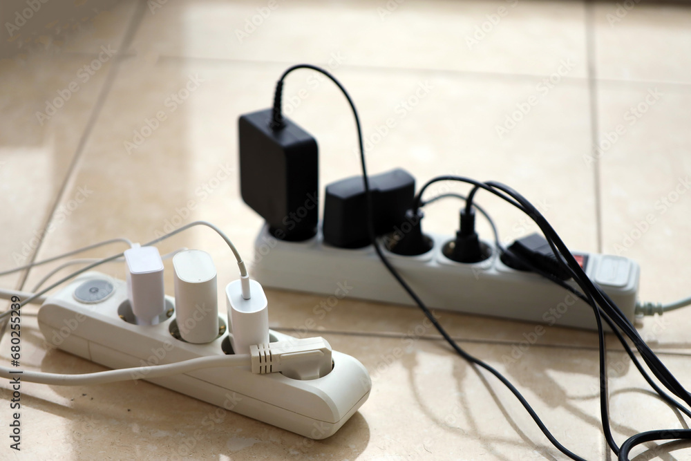 Overloaded power boards. Power strips with different electrical plugs on white floor. Concept of risk danger overloaded current electrical Overloaded power boards. Power strips with different electrical plugs on white floor. Concept of risk danger overloaded current electrical