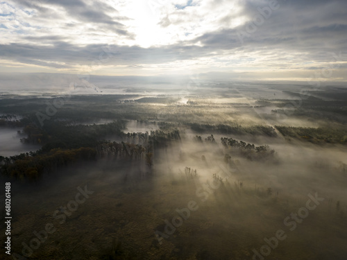 incredible foggy sunrise with beautiful rays of light over the misty valley forest, drone view from high above