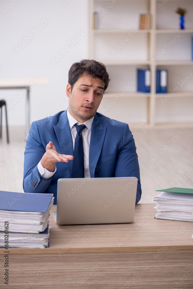 Young male employee and too much work in the office Young male employee and too much work in the office