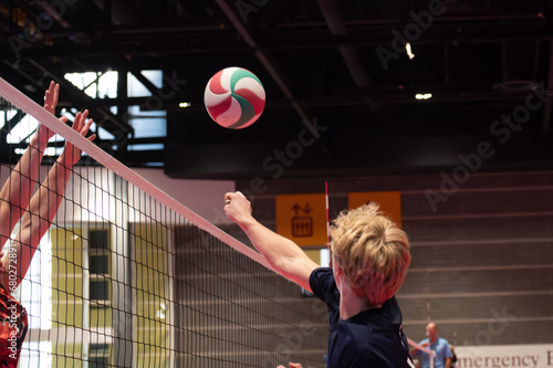 Volleyball player punching the ball over the net