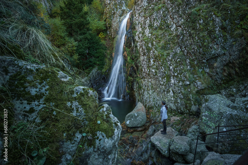 Woman standing at waterfall called Poco do Inferno with water pool during autumn time, Manteigas, Serra da Estrela, Portugal photo