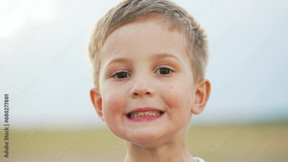 Portrait of a child. Cheerful happy kid boy in summer park at sunset. Dream kid child look into the camera on nature in the park. Toddler child playing outdoors on green grass portrait. Happy child Portrait of a child. Cheerful happy kid boy in summer park at sunset. Dream kid child look into the camera on nature in the park. Toddler child playing outdoors on green grass portrait. Happy child