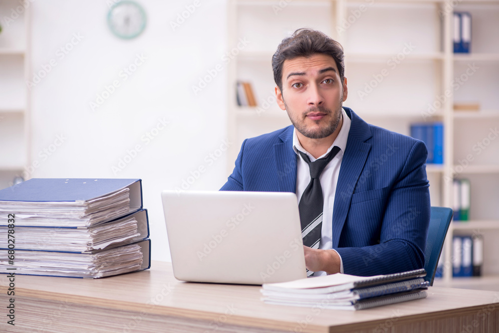 Young male employee and too much work in the office Young male employee and too much work in the office