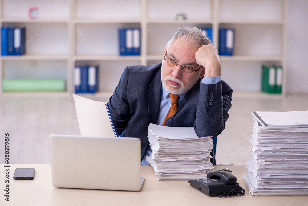 Old male employee unhappy with excessive work in the office Old male employee unhappy with excessive work in the office