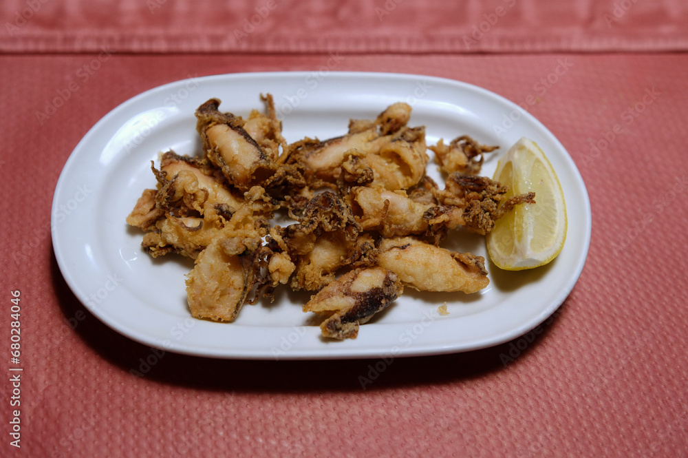 dish with fried squid with lemon slice dish with fried squid with lemon slice