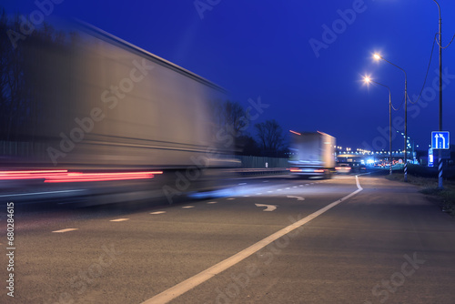 Trucks drive at night along the highway into the city.