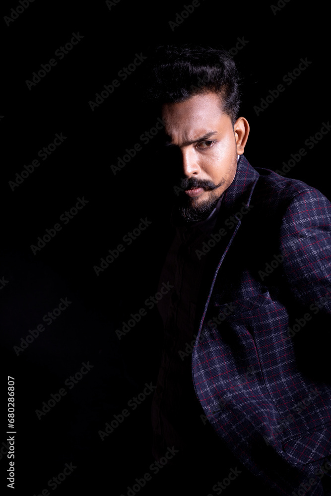 portrait of a businessman posing out and giving a serious look in black background