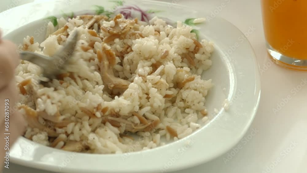 A person eating rice pilaf with chicken meat, A person eating rice pilaf with chicken meat,
