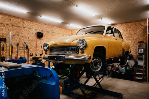 gelber Oldtimer Wartburg auf einer Hebebühne in einer Werkstatt