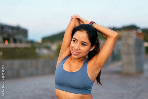 Smiling woman stretching outdoors after exercise photo