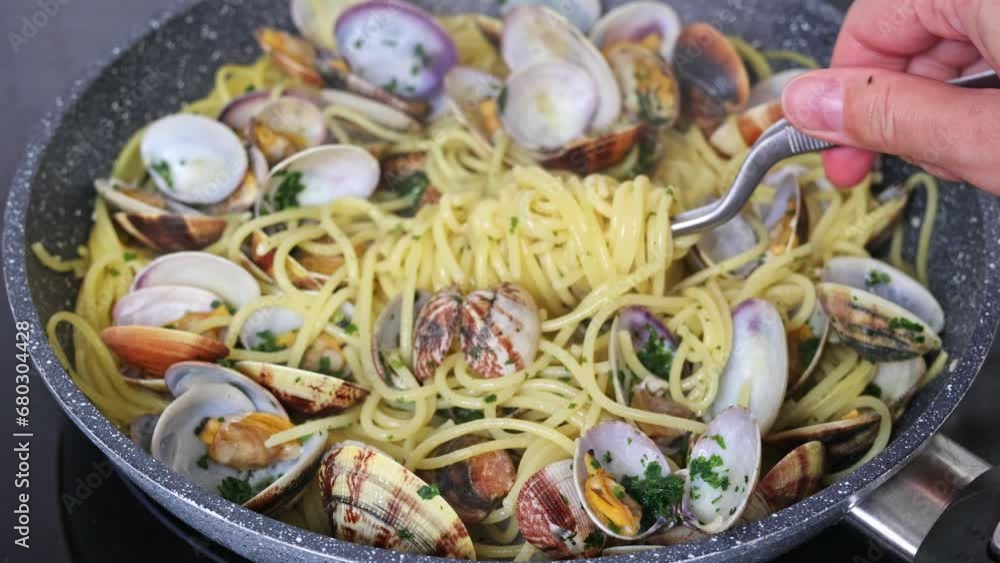 Cooking traditional italian seafood pasta with clams. Chef twists spaghetti for serving. Spaghetti alle Vongole. Cooking traditional italian seafood pasta with clams. Chef twists spaghetti for serving. Spaghetti alle Vongole.