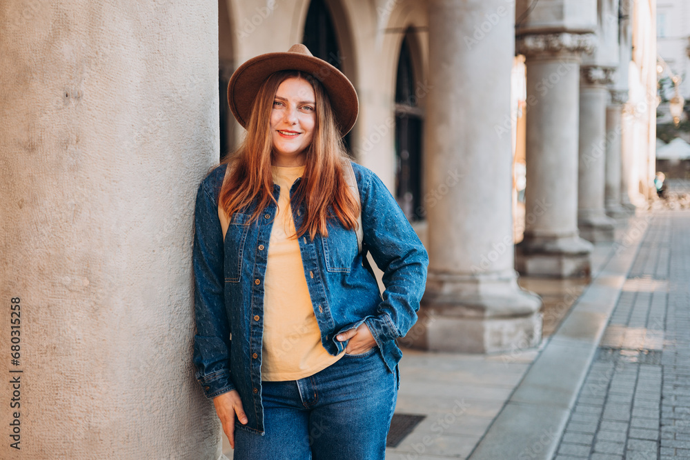 Attractive young female tourist is exploring new city. Redhead girl in hat posing on Market Square in Krakow. Traveling Europe in autumn. High quality photo, The Cloth Hall