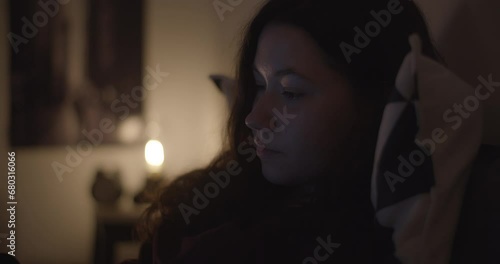 Beautiful woman in bed with tablet and earphones in dark room photo