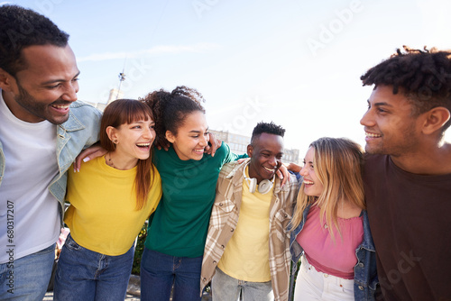 Multiracial young people team hugging together outdoor, diverse students and friends laughing. Smile happy carefree celebrating holidays. Concept unity, complicity and university community time. photo