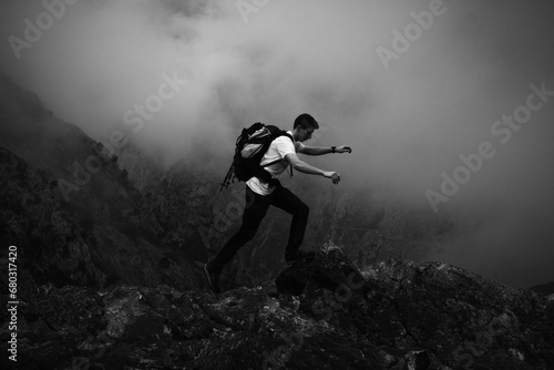 Montañero con una mochila saltando sobre unas piedras entre la niebla, Ruta del Cares, Asturias, España photo
