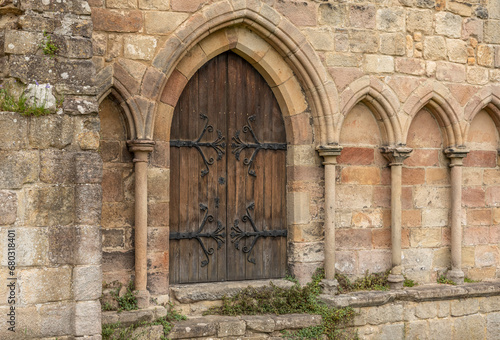 Ancient wooden arched doorway with decorative hinges