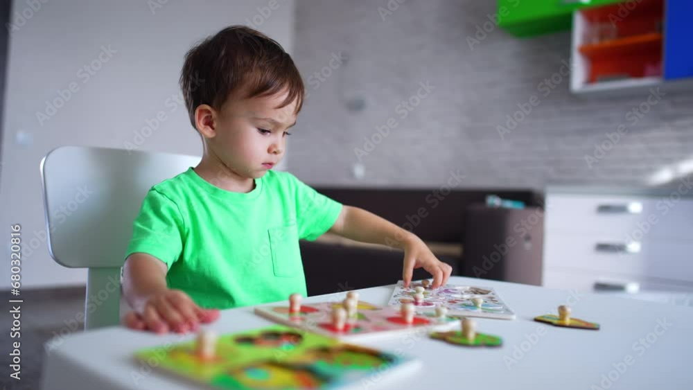 Lovely child playing with puzzles at desk. Focused toddler is busy with game at home. Blurred backdrop. Lovely child playing with puzzles at desk. Focused toddler is busy with game at home. Blurred backdrop.