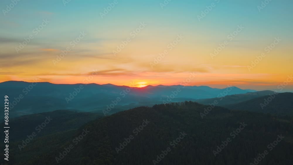 Aerial view of bright foggy morning over dark hills with mountain forest trees at autumn sunrise. Beautiful scenery of wild woodland at dawn Aerial view of bright foggy morning over dark hills with mountain forest trees at autumn sunrise. Beautiful scenery of wild woodland at dawn