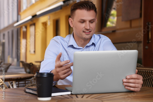 Handsome man working on laptop at table in outdoor cafe
