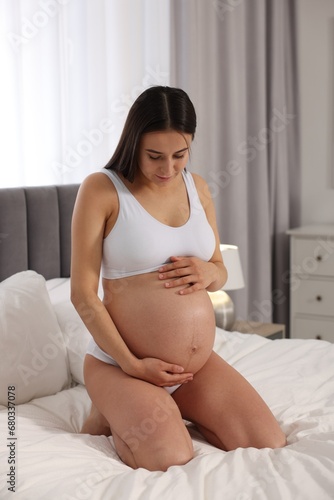Beautiful pregnant woman in stylish comfortable underwear on bed at home
