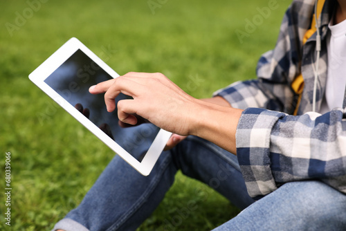 Student studying with tablet on green grass in park, closeup © New Africa