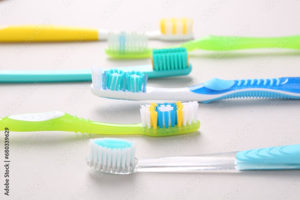 Many different toothbrushes on light background, closeup Many different toothbrushes on light background, closeup