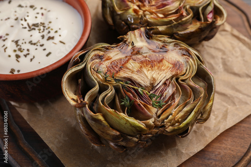 Tasty grilled artichoke and sauce on table, closeup