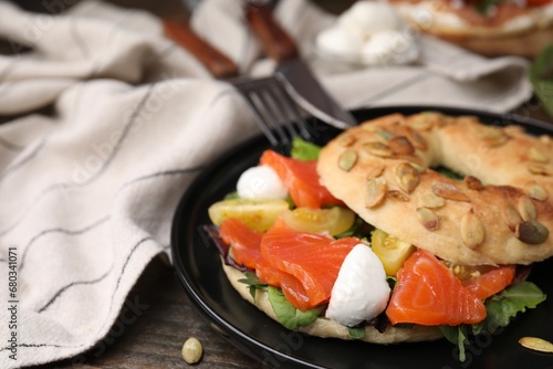 Tasty bagel with salmon, mozzarella cheese, tomatoes and lettuce on table, closeup. Space for text