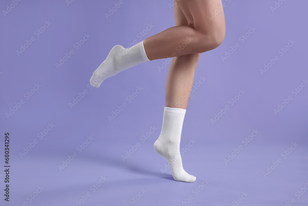 Fototapeta premium Woman in stylish white socks on violet background, closeup