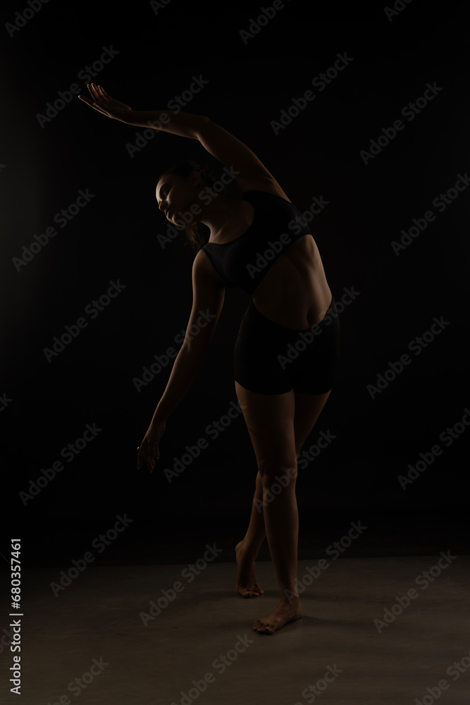 Fit Women Performing Yoga Postures Depicting Fitness in dull light and black background wearing black sports wear Fit Women Performing Yoga Postures Depicting Fitness in dull light and black background wearing black sports wear