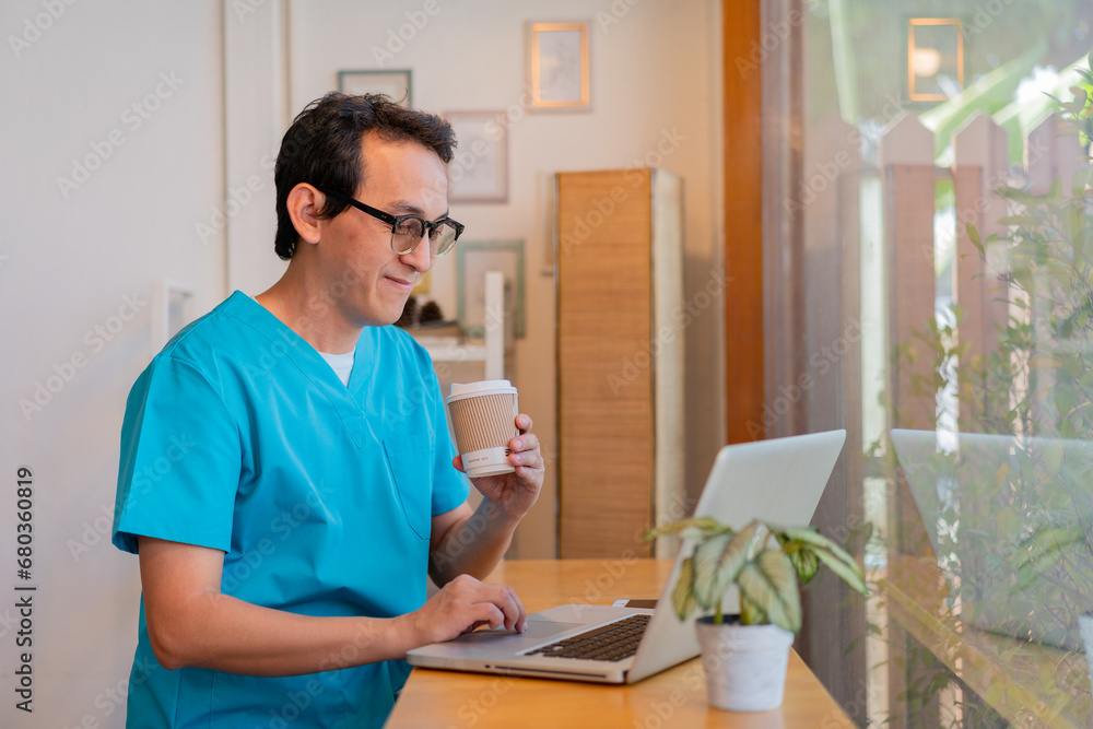 Smiling nurse using digital tablet in employee lounge. Male nurse takes a break outside of a coffee shop. Smiling nurse using digital tablet in employee lounge. Male nurse takes a break outside of a coffee shop.