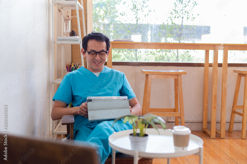 Smiling nurse using digital tablet in employee lounge. Happy nurse resting on couch in lounge area and drinking cup of coffee.