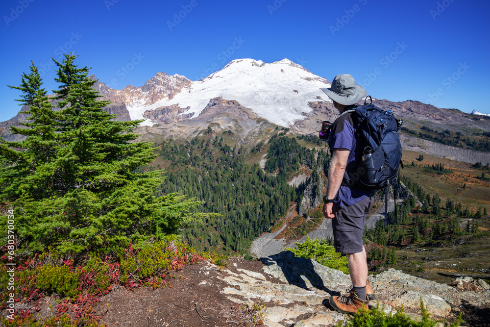 Adventurous athletic male hiker standing on top of a hill looking at Mount Baker on a beautiful sunny fall day in the Pacific Northwest.
Adventurous athletic male hiker standing on top of a hill looking at Mount Baker on a beautiful sunny fall day in the Pacific Northwest.