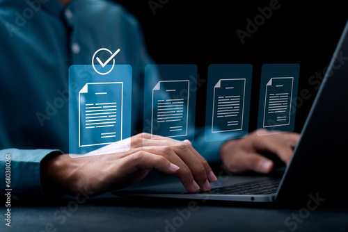 Document management concept, Businessman using laptop with online quality assurance approval document. Verifying electronic documents on digital documents, paperless document management system. photo