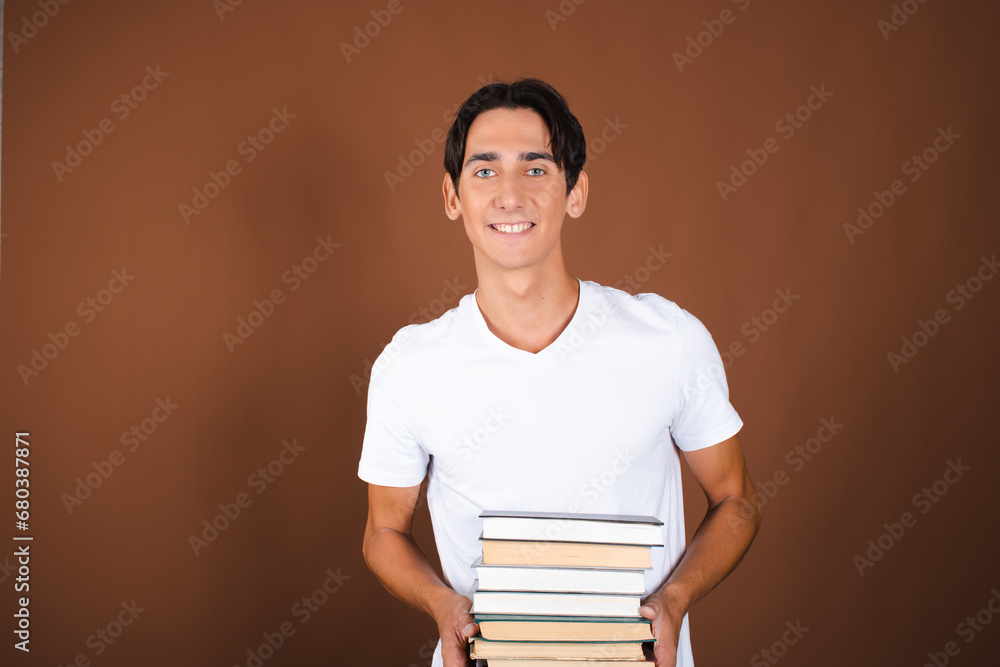 Funny student posing with books in studio on brown background. Funny student posing with books in studio on brown background.