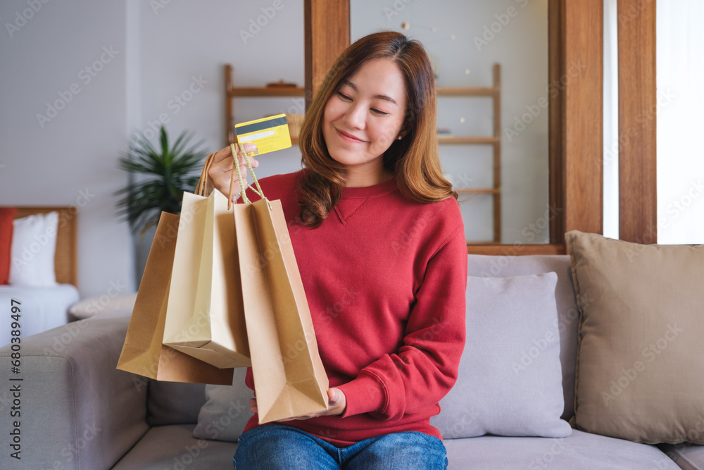 Portrait image of a woman with shopping bags holding and showing a credit card for purchasing Portrait image of a woman with shopping bags holding and showing a credit card for purchasing