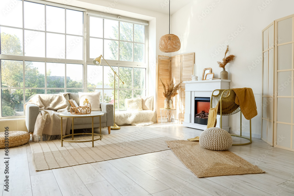 Fototapeta premium Interior of light living room with grey sofa, coffee table and fireplace