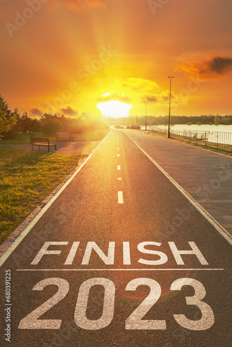 2023 year end concept. Motivational inscription for to summary the year. Number of the 2023 year and finish is written on the asphalt on the empty sports path in the bright rays of the sunset.