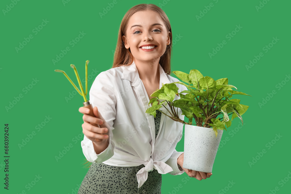 Female gardener with plant and rake on green background Female gardener with plant and rake on green background