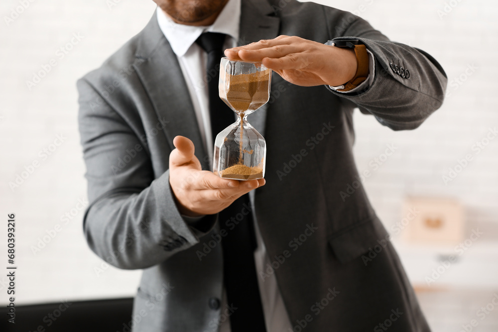 Young businessman with hourglass in office. Time management concept Young businessman with hourglass in office. Time management concept