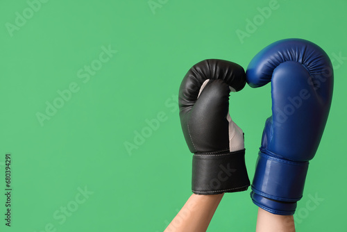 Female hands in boxing gloves on green background © Pixel-Shot