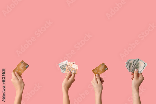 Female hands with credit cards and money on pink background
