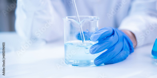 Closeup scientist hand using stirring rod for stirring blue liquid solution glass beaker chemical chemistry research science experiment test laboratory, scientific medicine technology lab analysis