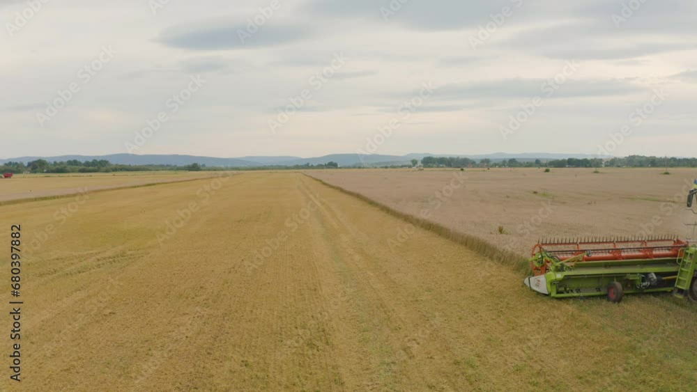 Aerial view of a combine harvester and agricultural machinery harvesting wheat. The work of machinery in the field during the harvest Aerial view of a combine harvester and agricultural machinery harvesting wheat. The work of machinery in the field during the harvest