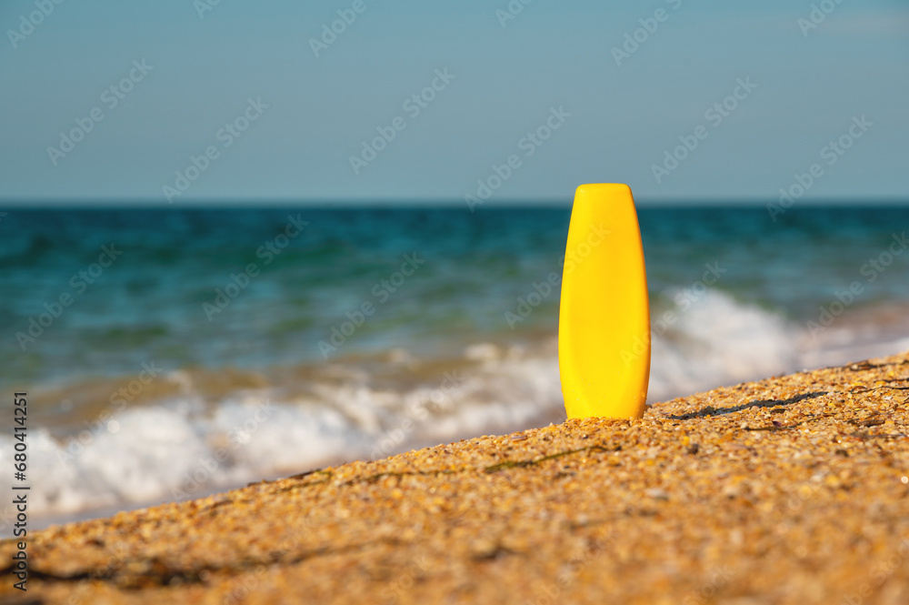 bottle of sunscreen on the sand against the background of the sea. Yellow tube of sunscreen on the beach close-up. Sun protection cosmetics concept bottle of sunscreen on the sand against the background of the sea. Yellow tube of sunscreen on the beach close-up. Sun protection cosmetics concept