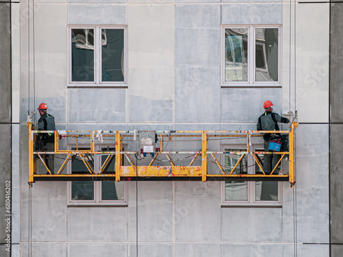 Lifting platform for construction workers working on the facade of a building paint catching seams construction theme