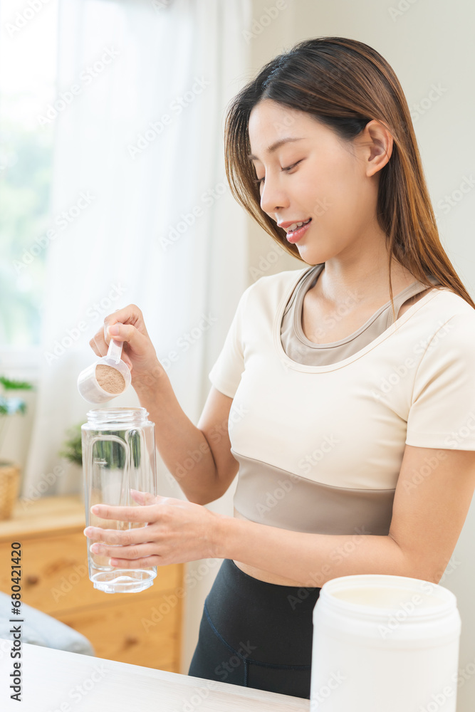 Diet meal replacement for weight loss, asian young woman in sportswear, hand in holding scoop making protein into bottle to shake, drink supplement for muscle after workout at home. Healthy body care. Diet meal replacement for weight loss, asian young woman in sportswear, hand in holding scoop making protein into bottle to shake, drink supplement for muscle after workout at home. Healthy body care.