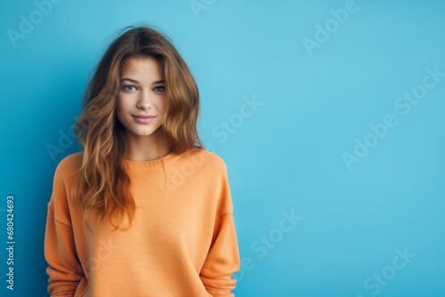 Beautiful girl wearing orange sweater against blue background, copy space, banner