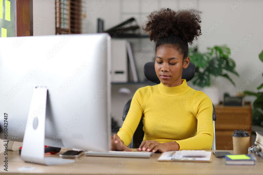 Attractive african american woman working with computer and financial documents in office. Attractive african american woman working with computer and financial documents in office.
